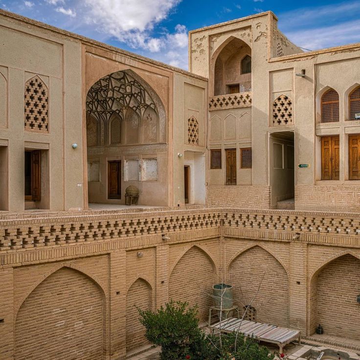 the courtyard of an old building with stone walls and arches on each side, surrounded by greenery