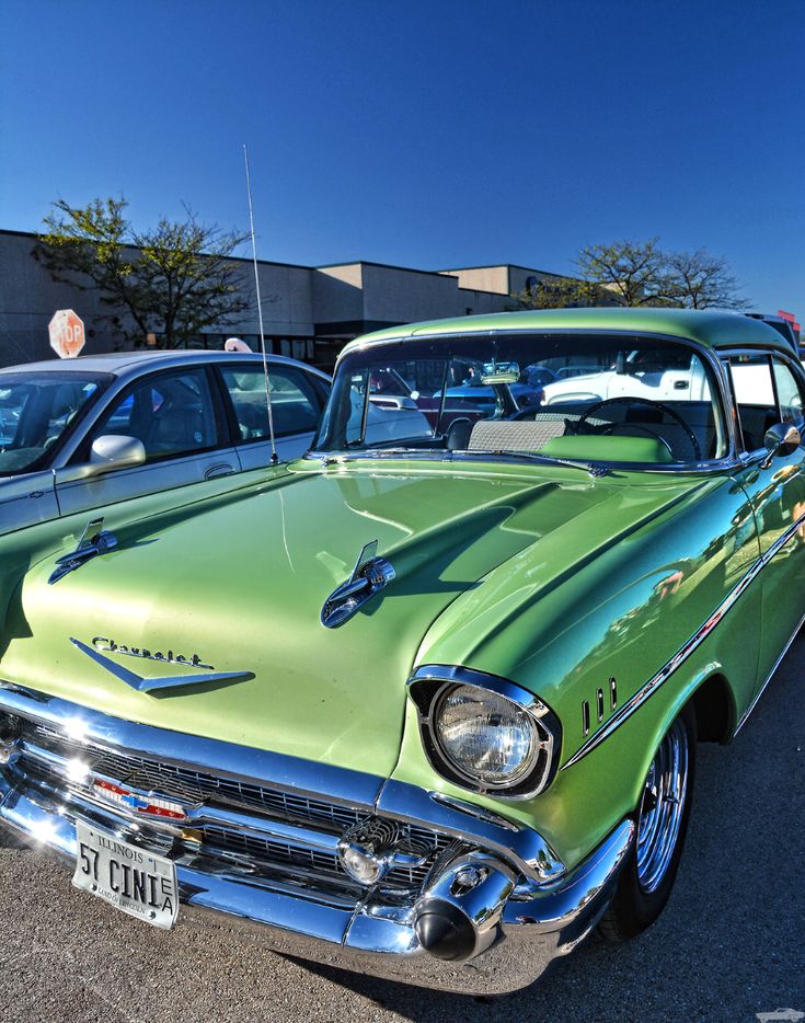 an old green car parked in a parking lot