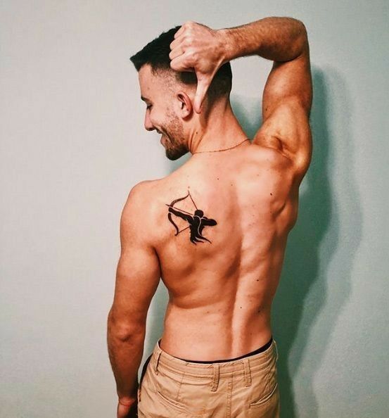 a man with a tattoo on his back is holding his hand up to his head