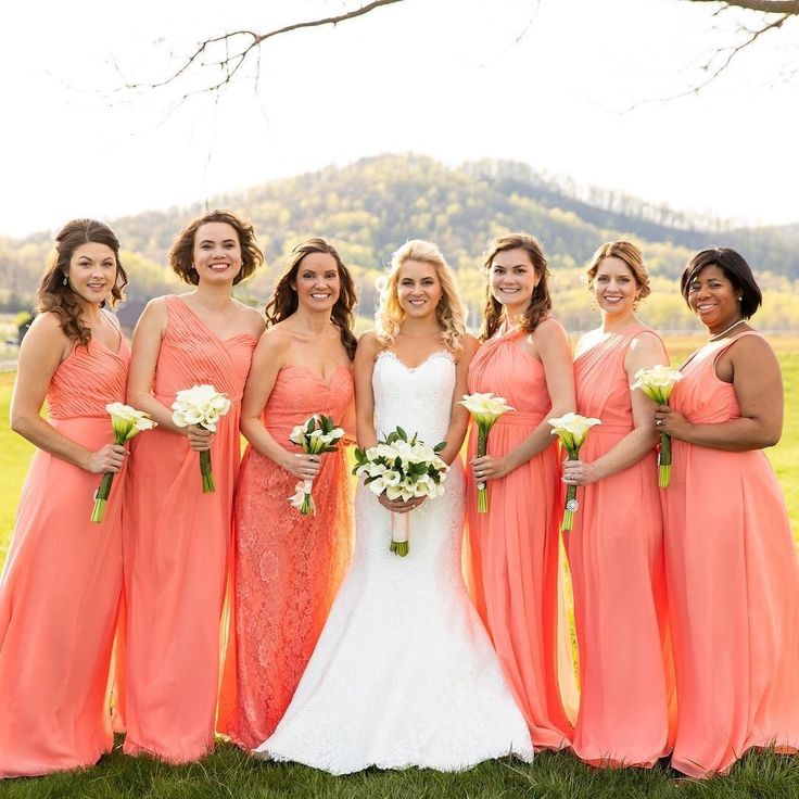 a group of women standing next to each other in front of a lush green field