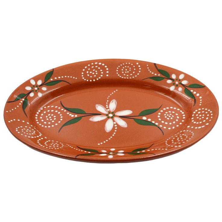 an orange platter with white flowers and green leaves on the rim, sitting on a white background