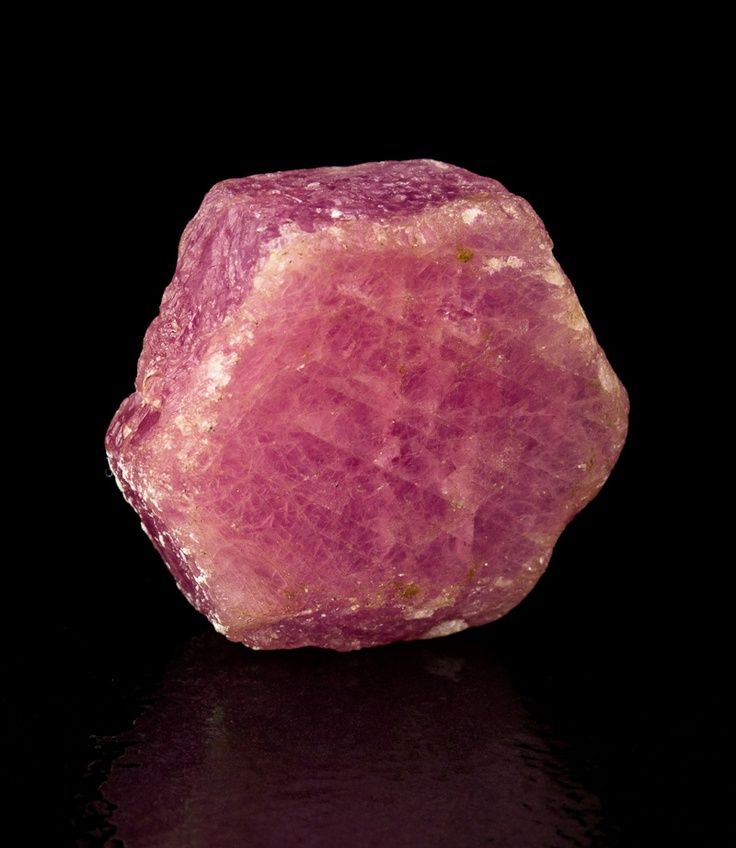 a pink rock sitting on top of a black surface