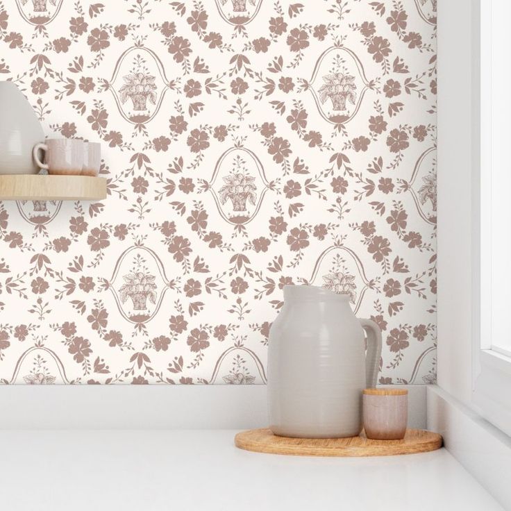 a white vase sitting on top of a counter next to a cup and saucer