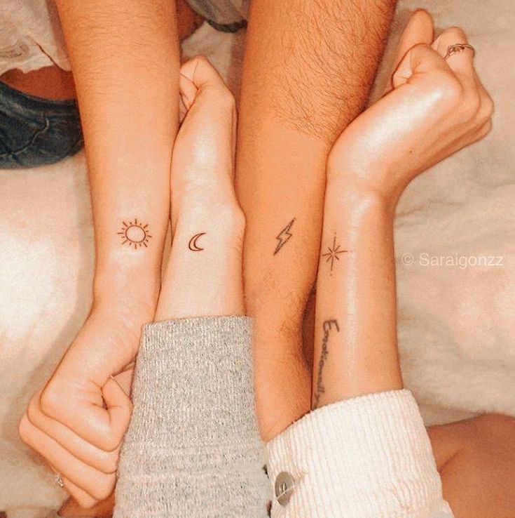 two people with matching tattoos on their arms and legs, one holding the other's hand