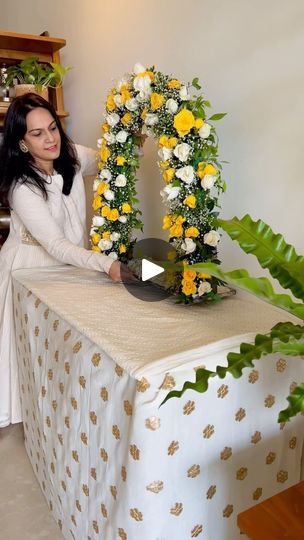 a woman standing next to a table with flowers and a wreath on top of it