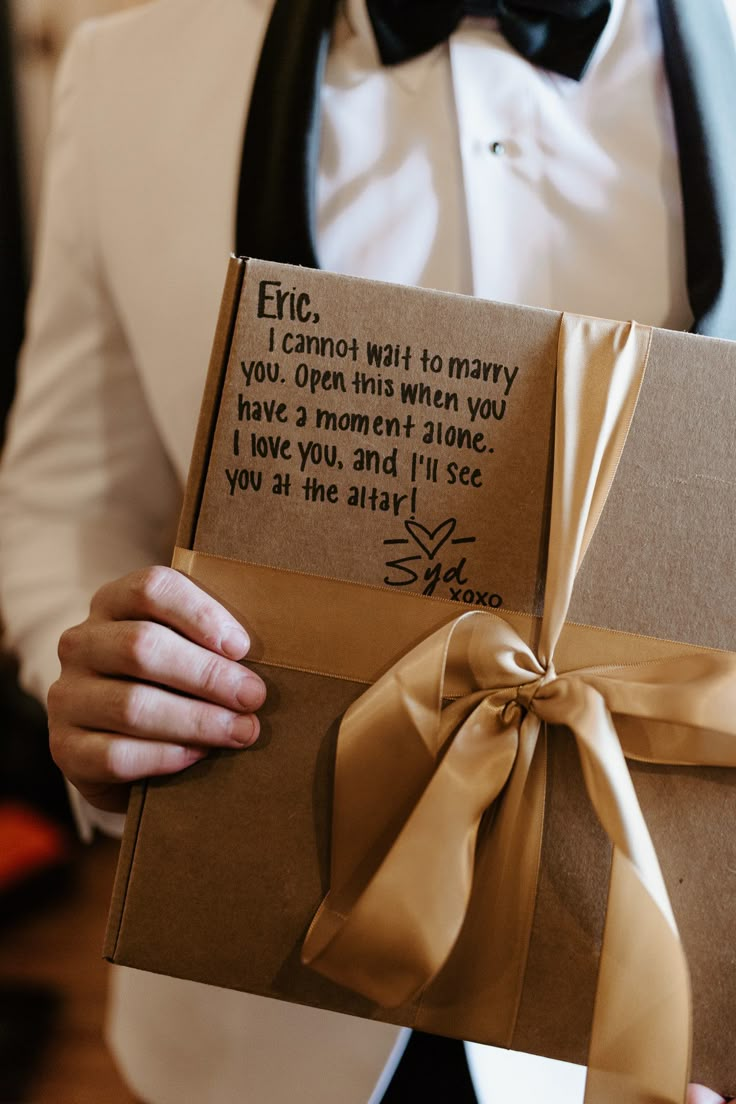 a man in a tuxedo holding a brown box with a poem on it