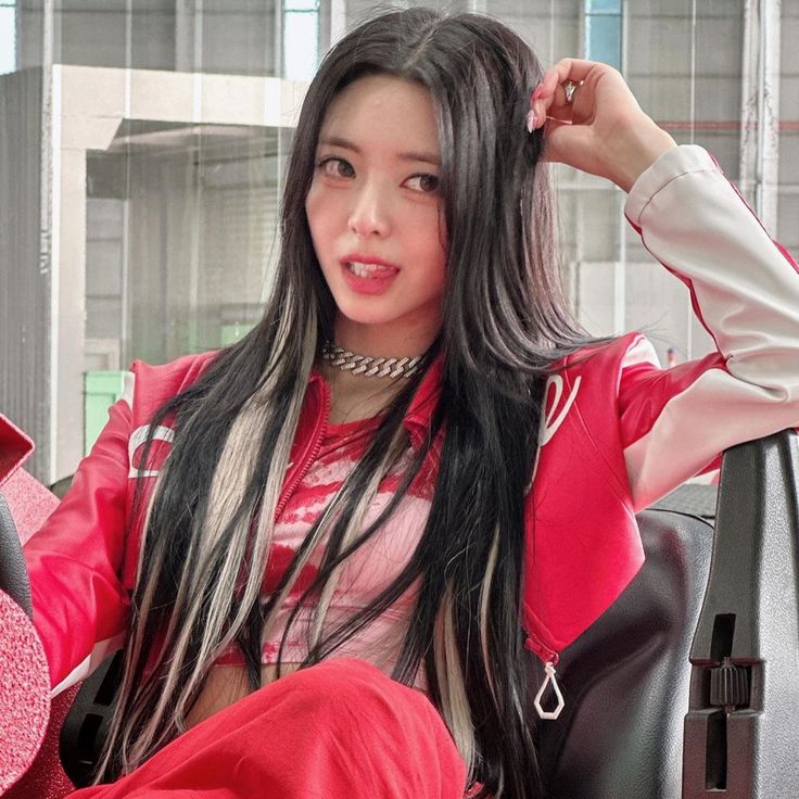 a woman with long black hair sitting in a red chair and posing for the camera