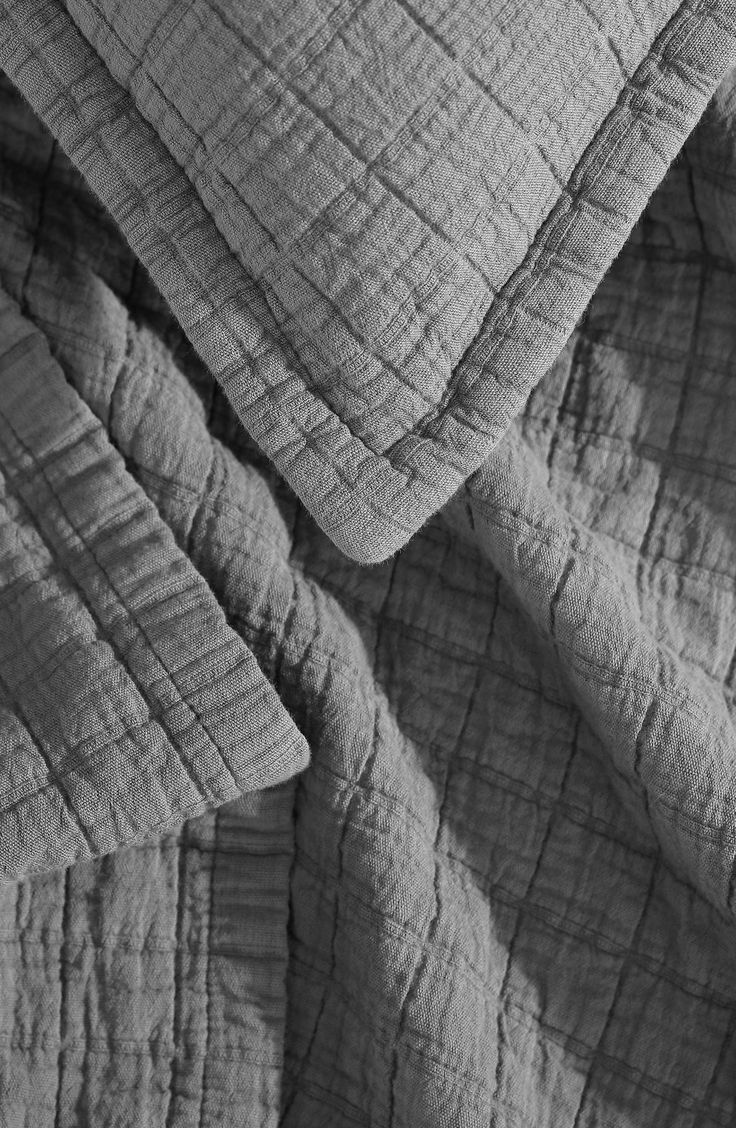 black and white photograph of an unmade bed with sheets folded over the top to make it look like they are made out of fabric