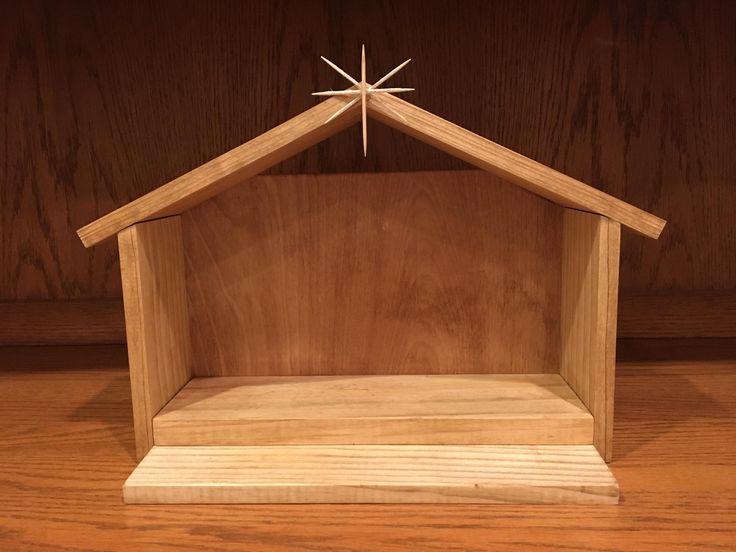 a small wooden nativity scene with a star above the top on a wood surface