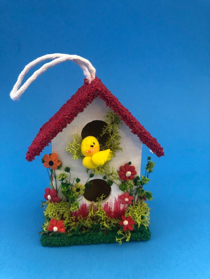 a birdhouse with flowers and a rubber duck in the center on a blue background