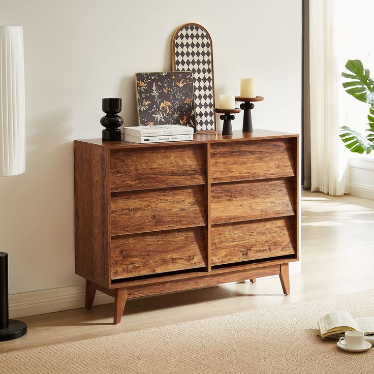 a wooden dresser sitting on top of a hard wood floor next to a white wall