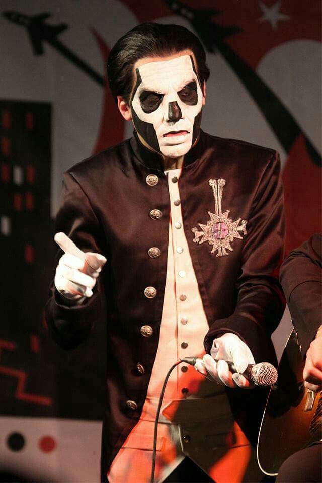 a man in a costume holding a guitar and wearing a skeleton face paint on his face