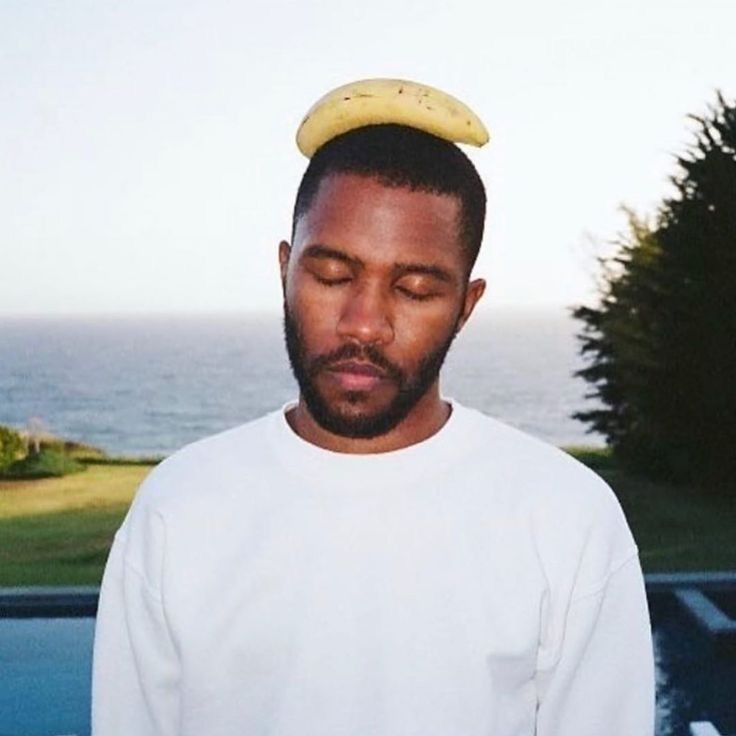 a man with a banana on his head standing in front of a pool near the ocean