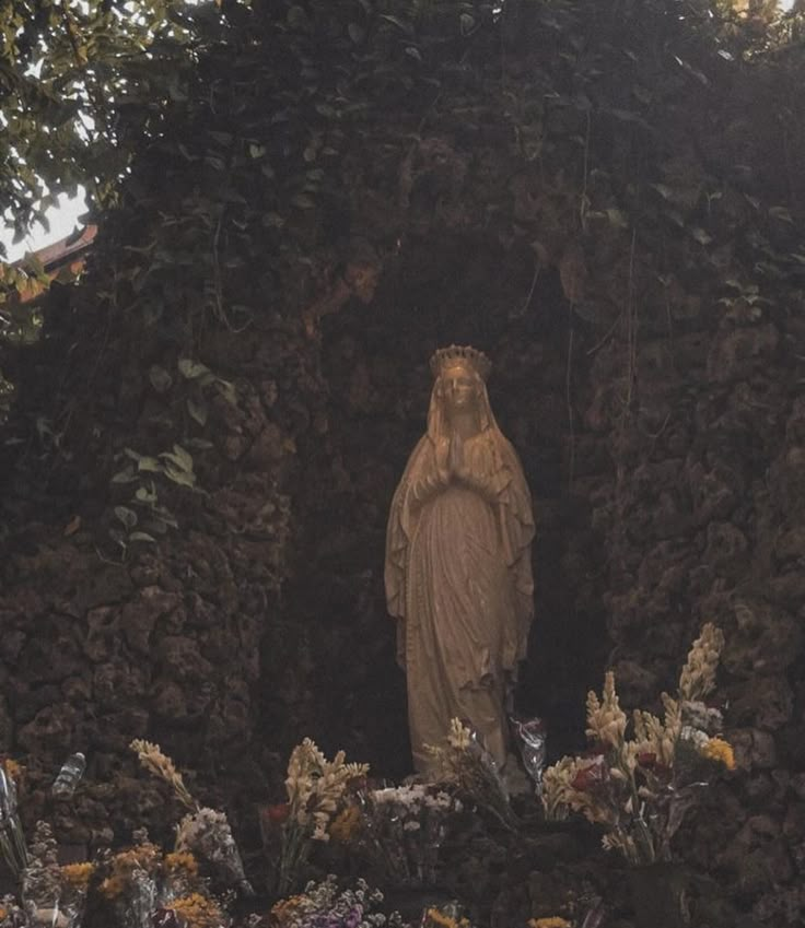 a statue in the middle of a garden surrounded by flowers