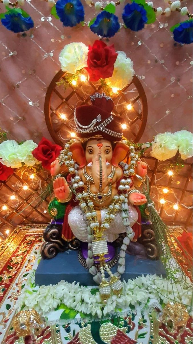 an elephant statue sitting on top of a blue box surrounded by flowers and garlands