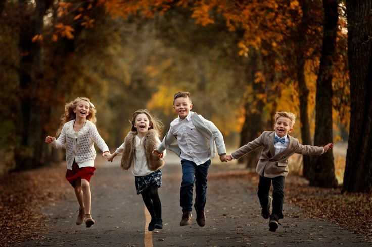 three young children running down a path in the woods with their arms around each other