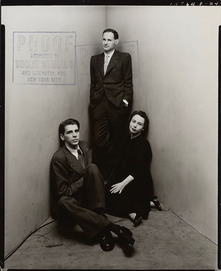 two men and a woman sitting on the floor in front of a wall with writing on it