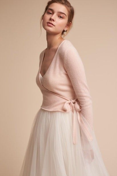 a woman in a white dress and pink sweater