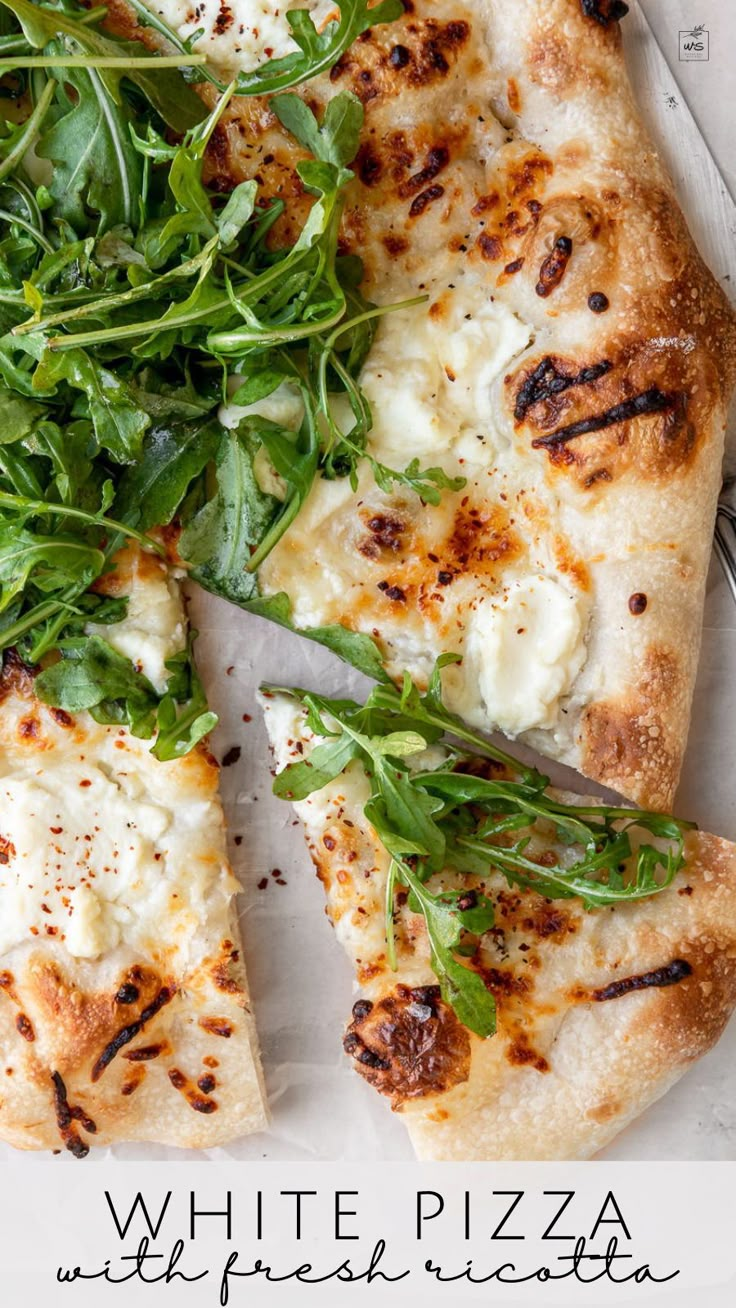 a pizza with spinach and cheese on it is cut into four slices, sitting on a piece of parchment paper