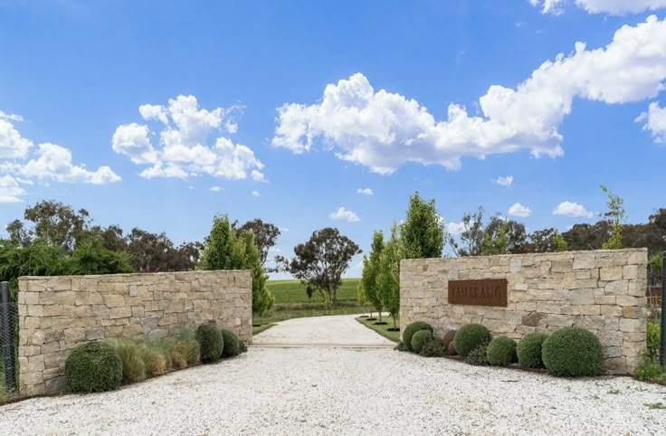 a stone wall and gate leading to a grassy field