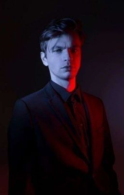 a man in a black suit with red light coming from his eyes and chest, standing against a dark background