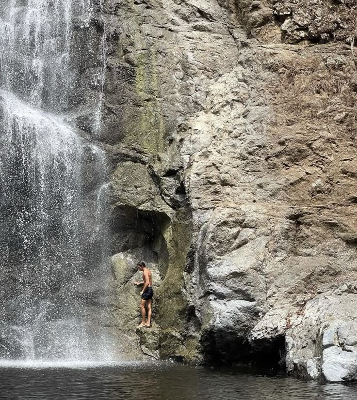 a man standing in front of a waterfall