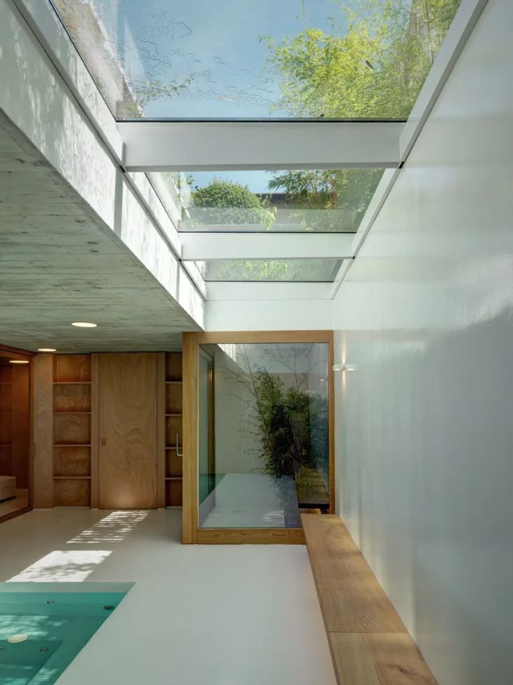 an indoor swimming pool in the middle of a room with glass walls and skylights