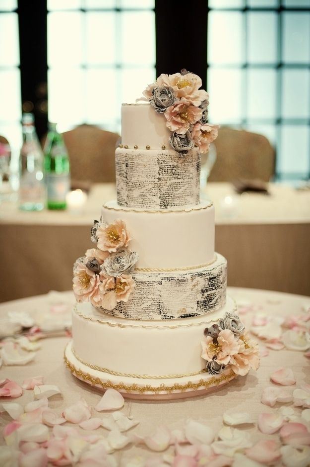 a three tiered wedding cake with flowers on the top and bottom, sitting on a table