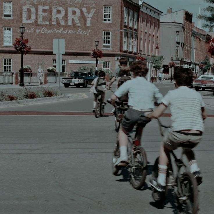 several people riding bikes down the street in front of buildings with old signs on them