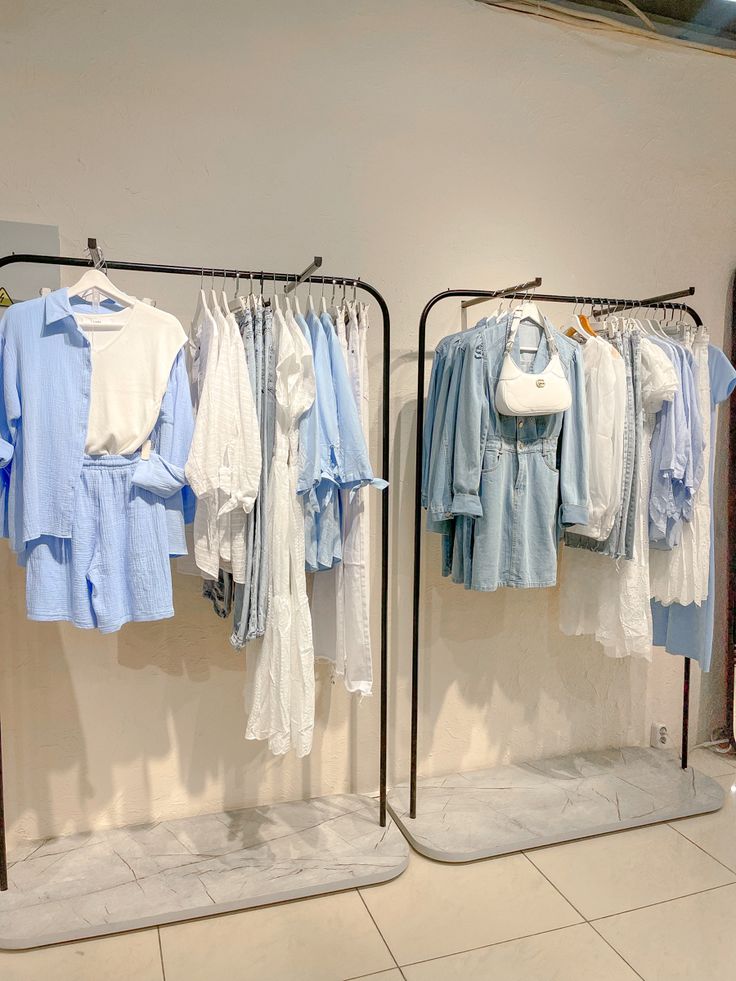 two racks with clothes hanging on them in front of a mirror and tiled flooring