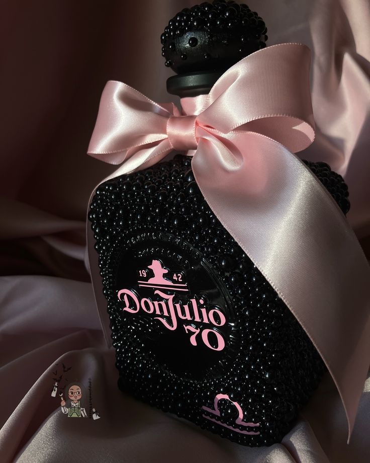 a black perfume bottle with a pink bow on it