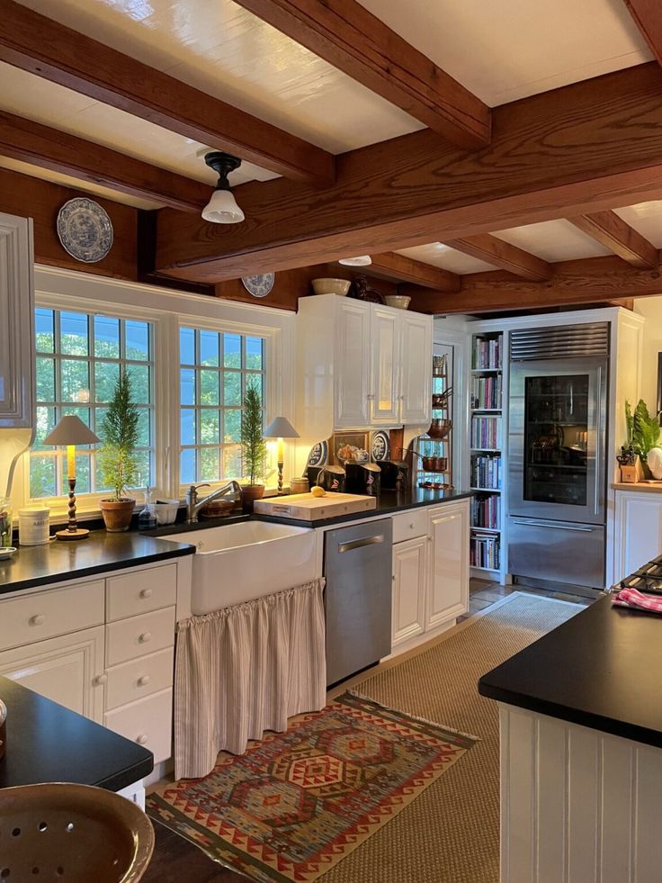 a large kitchen with white cabinets and black counter tops, along with an area rug on the floor