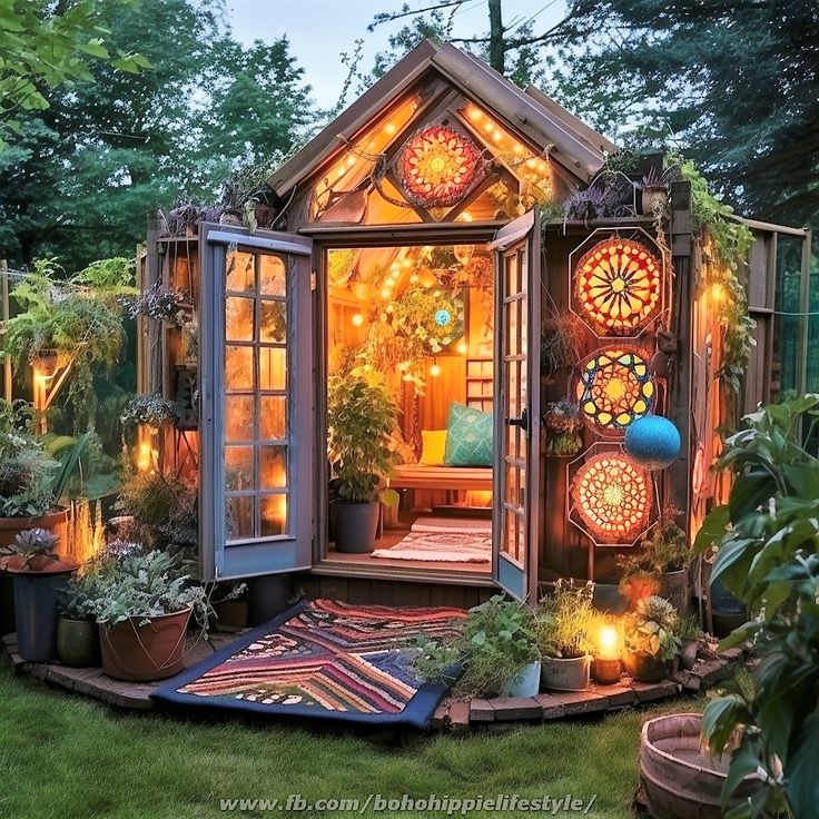 a small garden shed is lit up with fairy lights and potted plants in the yard