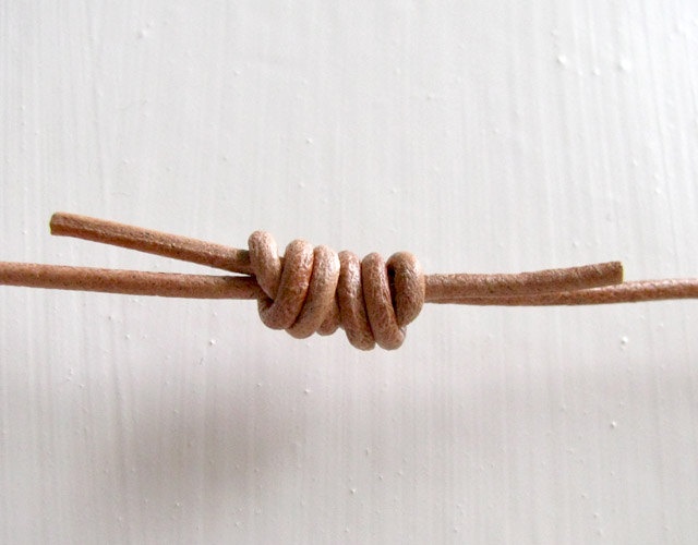 a close up of a knot on a white surface with some brown string attached to it