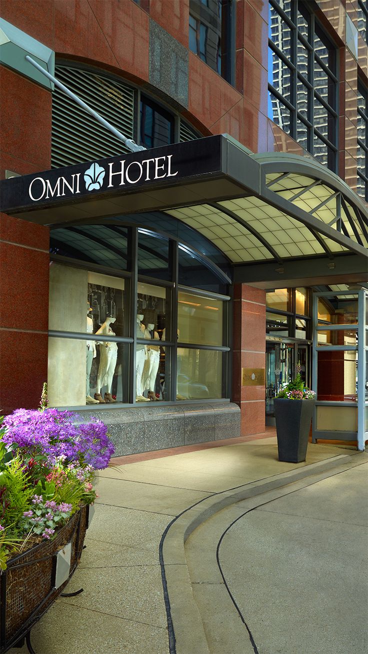 a hotel entrance with flowers in the foreground and a train track running through it