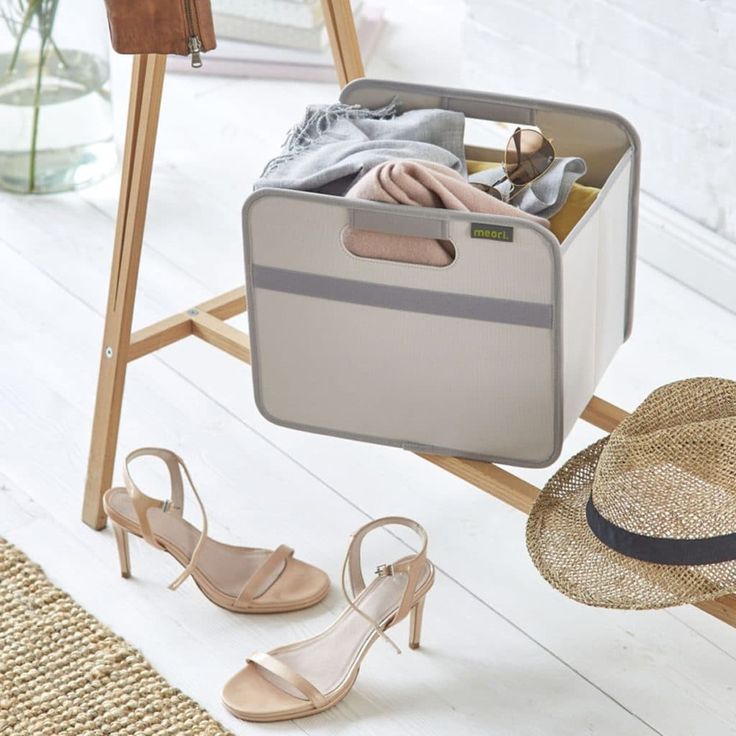 an open suitcase sitting on top of a wooden floor next to shoes and a hat