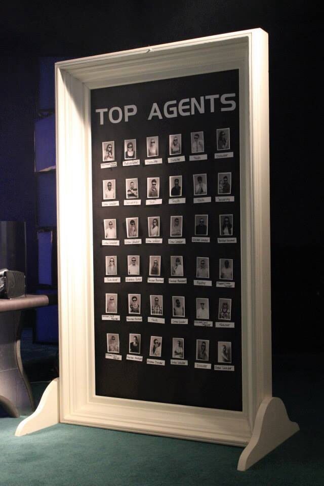 a top agent's poster is on display in front of a chair and table