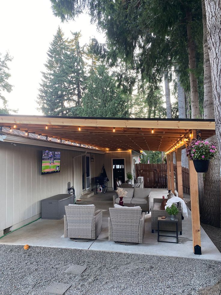 a patio covered with furniture and lights next to trees