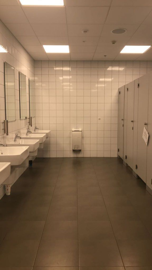 a public restroom with three sinks and two urinals