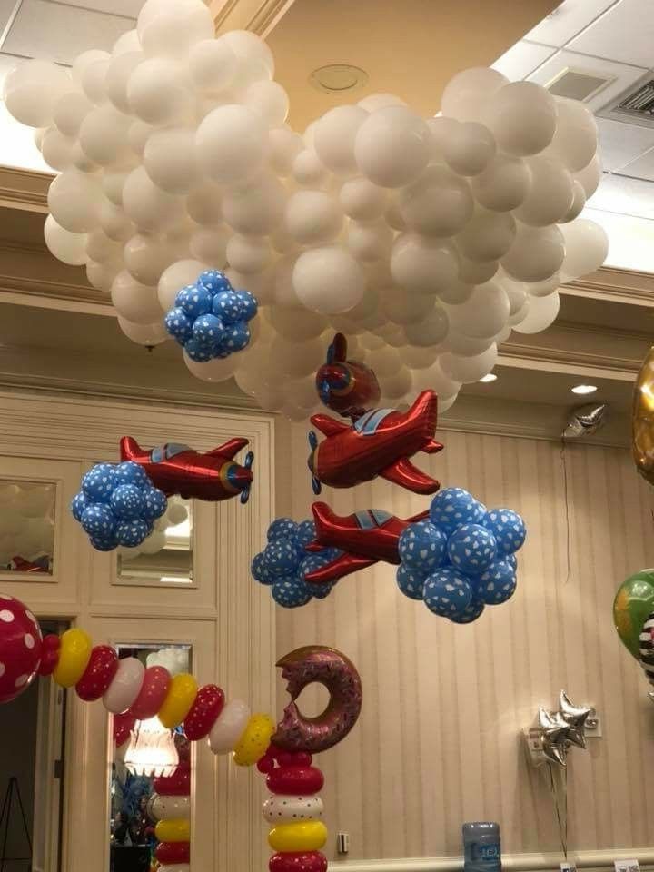 some balloons are hanging from the ceiling in front of a wall with an airplane on it