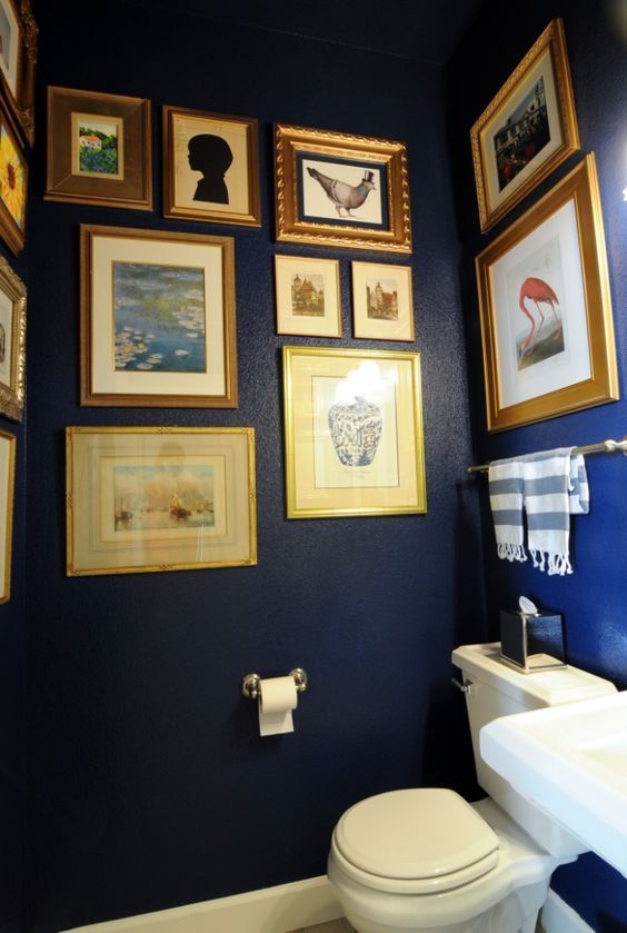 a white toilet sitting next to a bathroom sink under pictures on the wall above it