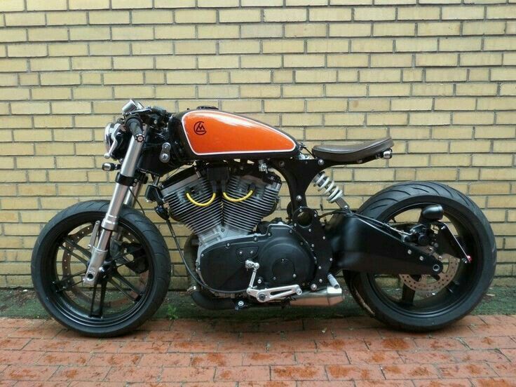 an orange and black motorcycle parked in front of a brick wall