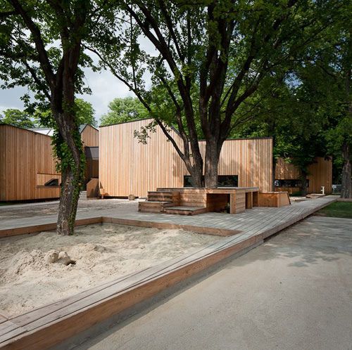 an outdoor area with sand and trees in the middle, surrounded by wooden structures on either side