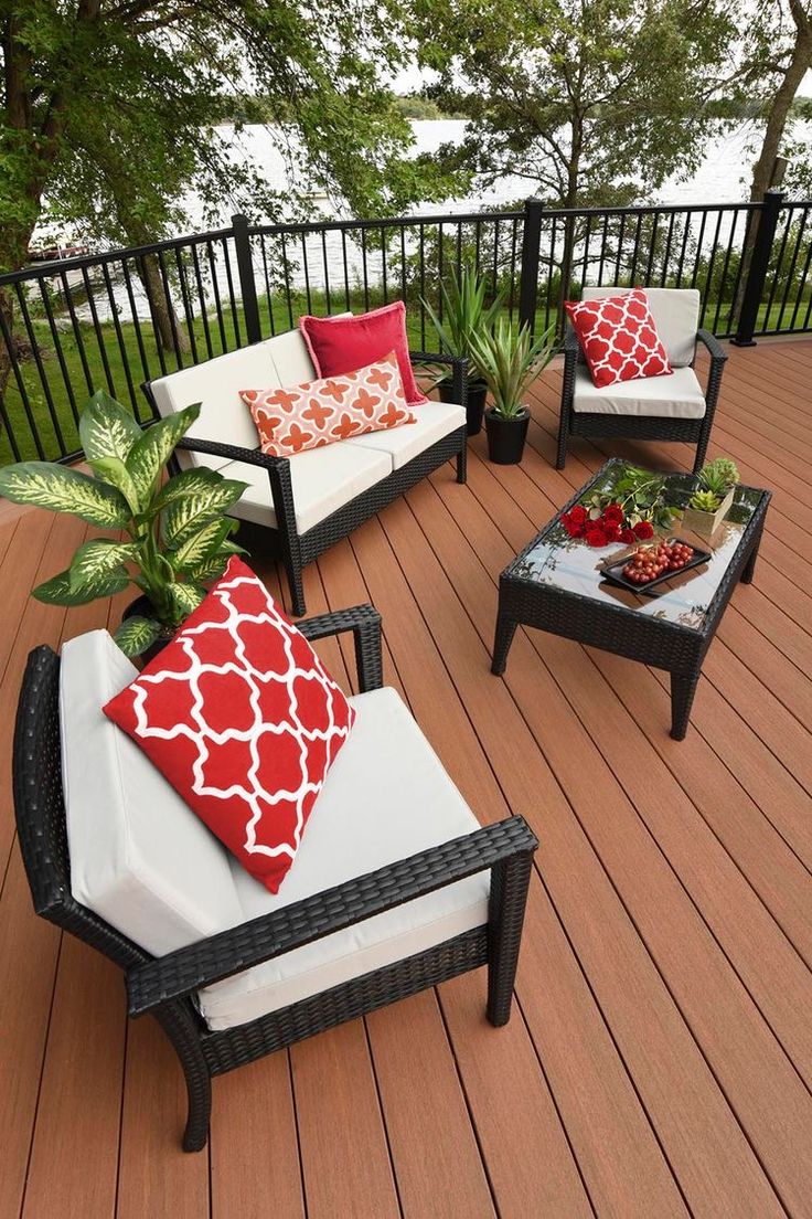 an outdoor deck with chairs, tables and pillows on the top floor next to trees