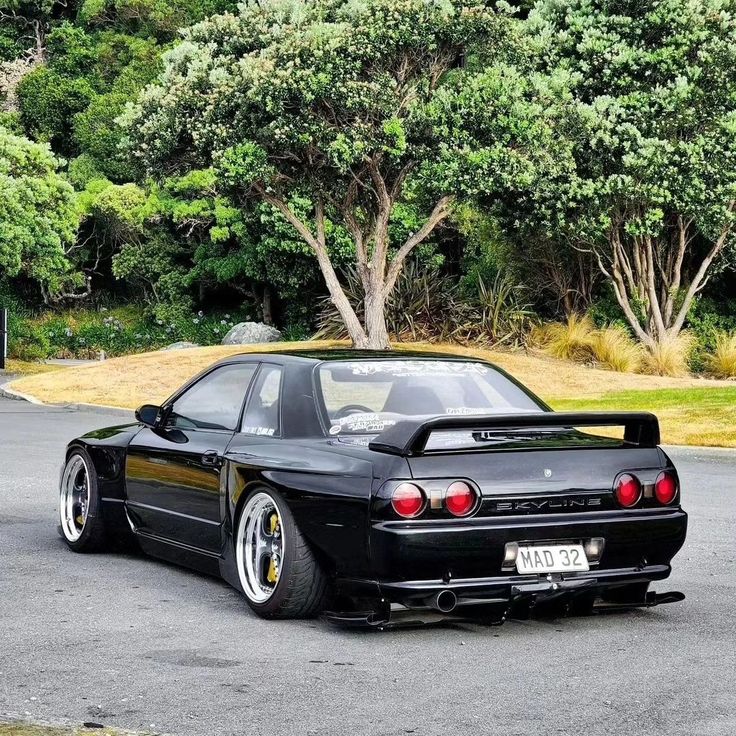 a black sports car parked in front of some trees