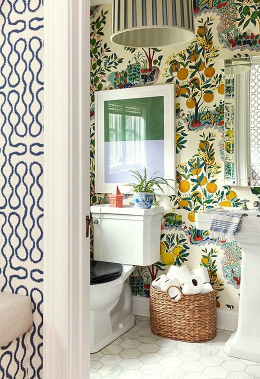 the bathroom is decorated with colorful wallpaper and white fixtures, along with a wicker basket on the floor