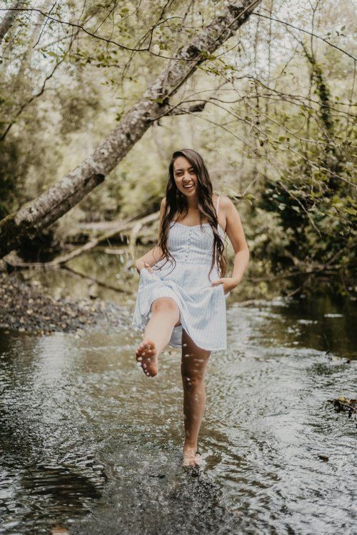 a woman is standing in the water and holding onto her leg while she's smiling