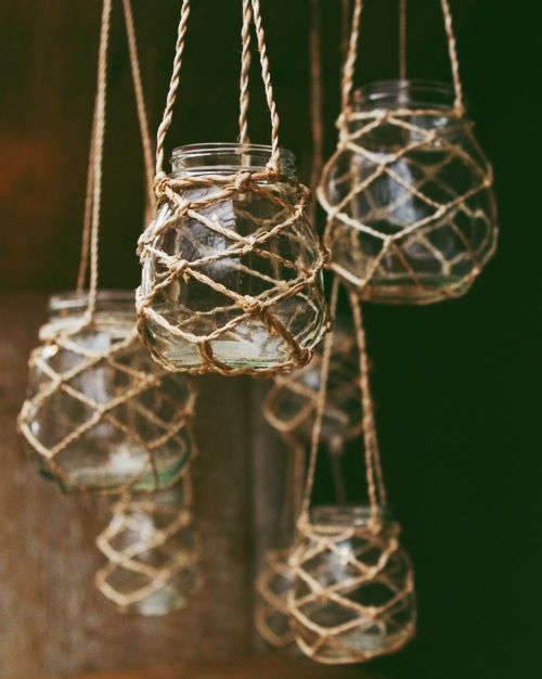 several glass jars hanging from rope with water in them