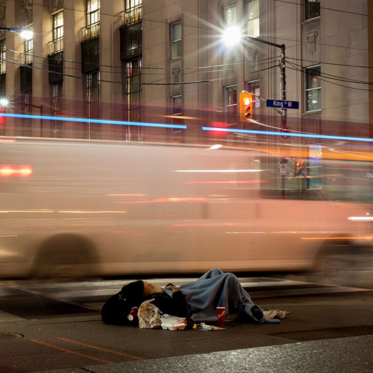 a person laying on the ground in front of a street with cars passing by at night