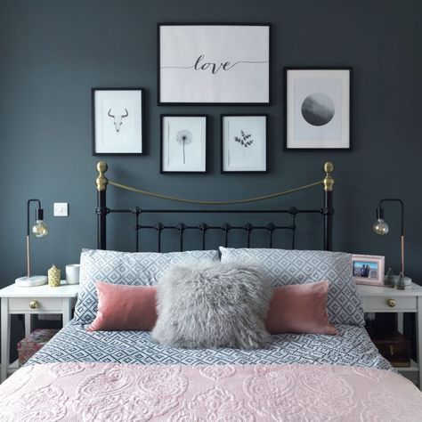 a bedroom with blue walls and pictures on the wall above the bed, along with pink pillows